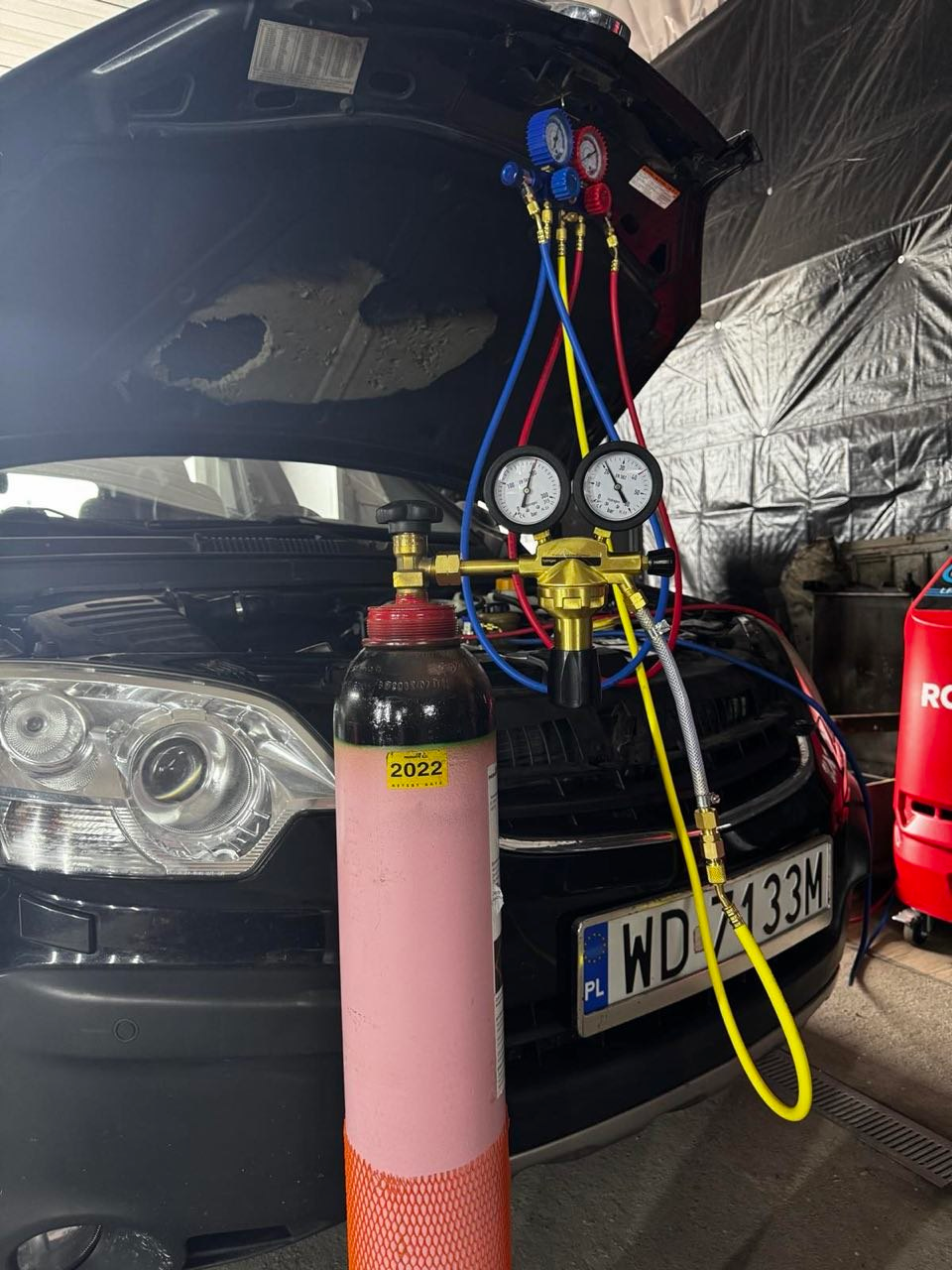 Car A/C service equipment connected to a vehicle